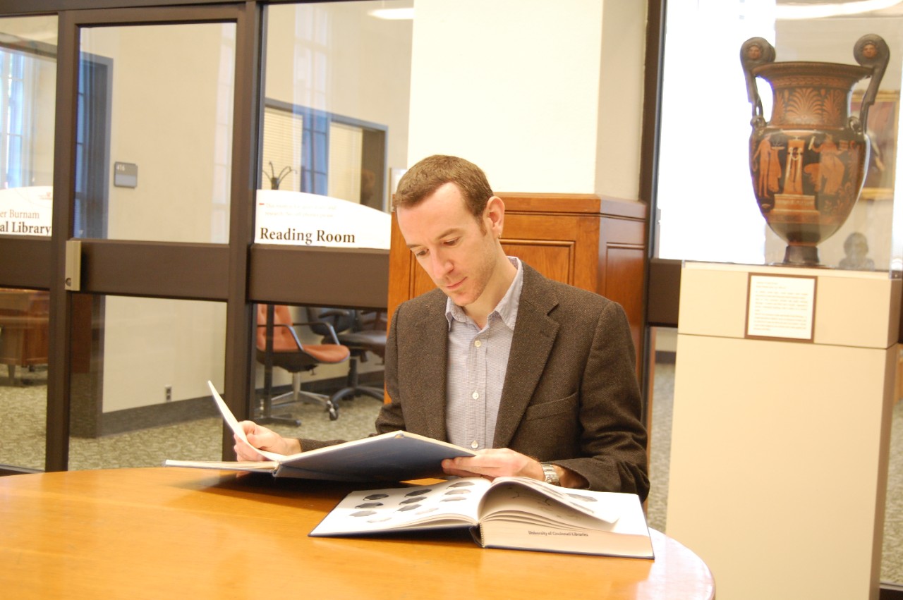 A student flips through a book in the Classics library. A student flips through a book in the Classics library.