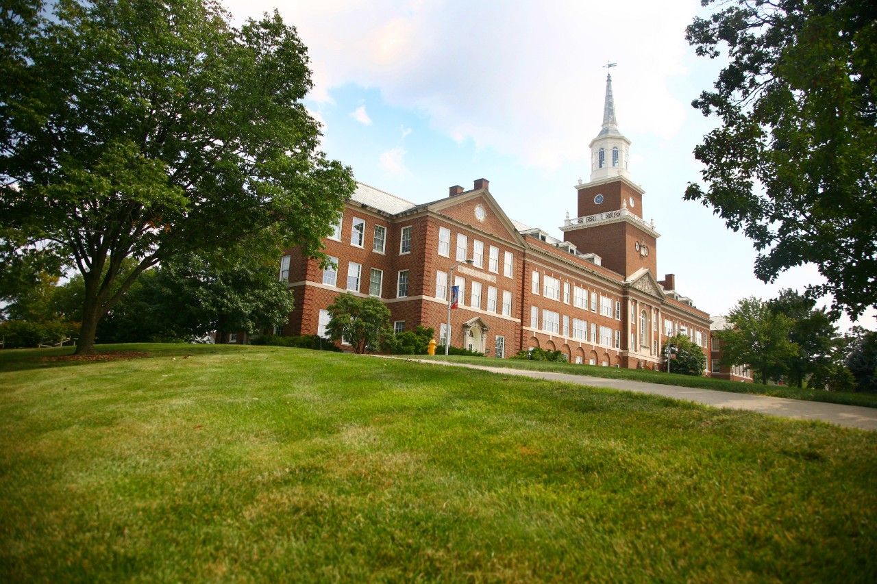 A view of Arts and Sciences Hall at the top of a green hill.